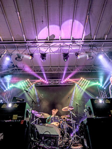 A band is performing on stage with vibrant lighting and various musical instruments, creating an energetic atmosphere.